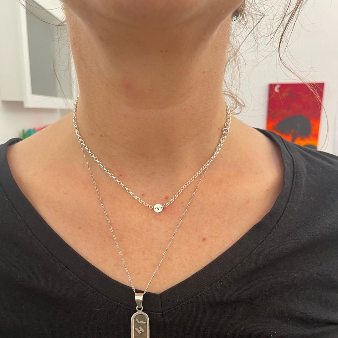 A close-up of a custom-fitted permanent necklace with a small charm pendant, emphasizing the delicate and meaningful design by Aura Eternity.