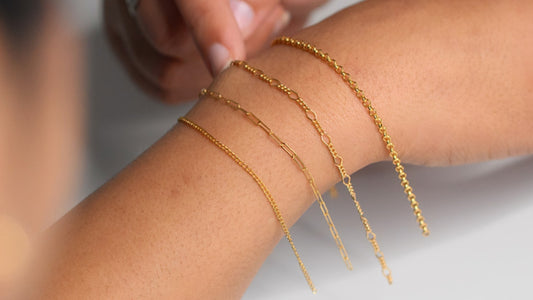 Several gold bracelets being displayed on a wrist, showcasing different intricate designs.